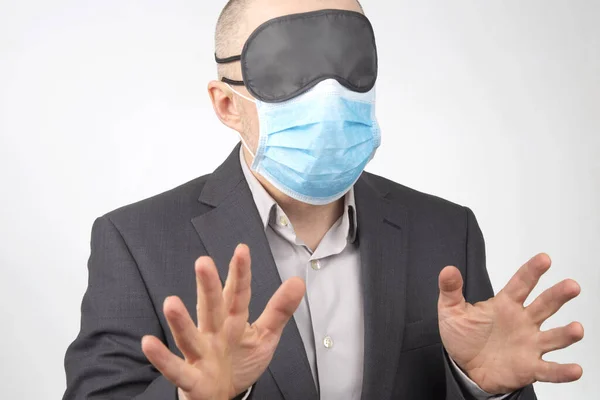 business man in a medical mask and blindfold for sleeping with hands up on a white backgroun