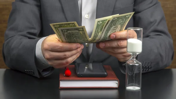 business man in the office counts money on a background of sundials. business and remuneration.