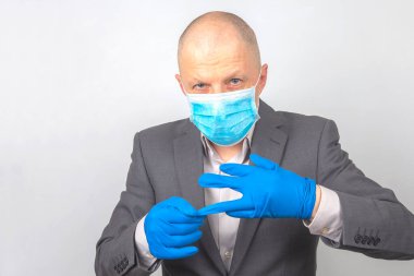 Tıbbi maskeli bir iş adamı ellerindeki koruyucu eldivenleri çıkarır. virüs karantinası