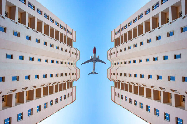 Passenger plane flies in the sky against the background of two multi-storey modern buildings. transport and construction industr