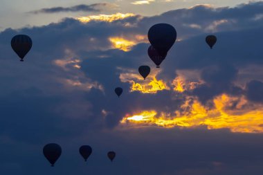 Birçok yolcu balonu bulutlarda şafak vakti arka planda uçar.