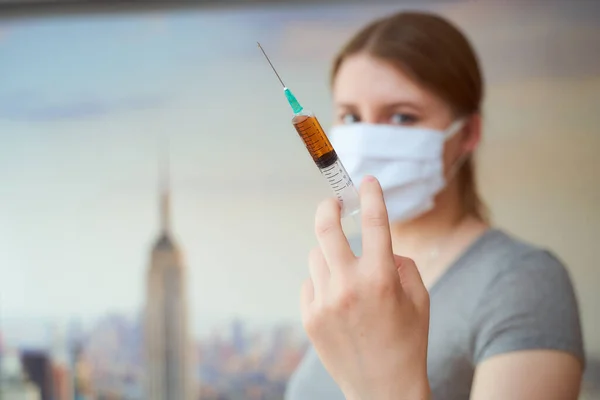 New York 'ta elinde şırıngayla koruyucu maskeli bir kız.