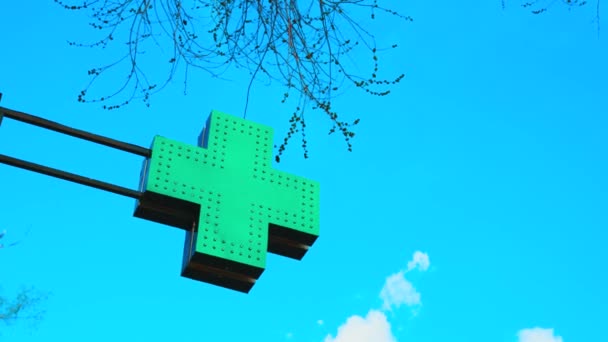 A sign in the form of a cross or plus sign against the sky. Green pharmacy cross with LEDs. Advertising sign — Stock Video