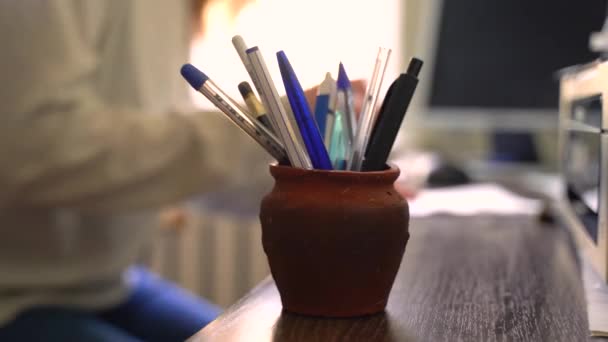 少女は鉛筆で花瓶に来て そのうちの1つを取り 背景に書き始めます — ストック動画