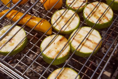 Izgarada kabak ve sosis pişirmek için sebzeler demir ızgara kapama efektinin üzerinde yatar.