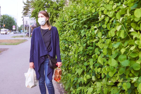 一个身穿蓝色夹克的小女孩站在身穿医用面罩的绿色灌木旁边 照片质量很高 — 图库照片
