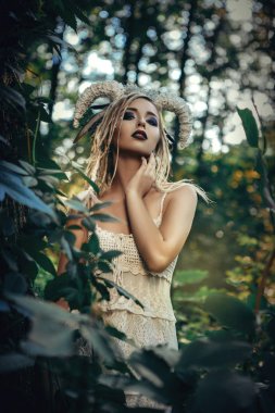 Güzel model beyaz boynuzları olan bir ormandaki poz 