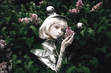 Genç bir kız çiçeklerin arasında uzaylı kılığına girmiş.