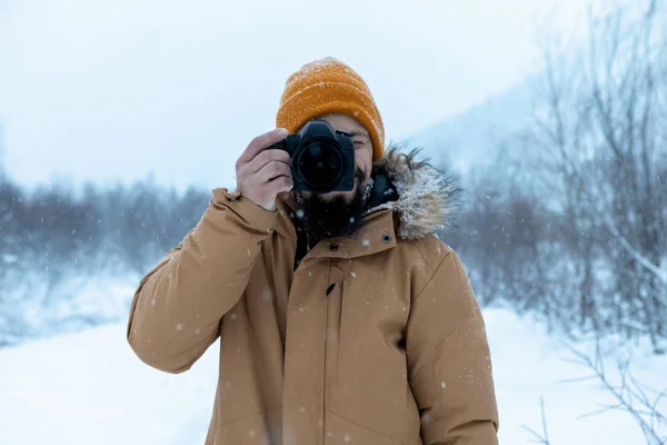 Un hombre con barba en el bosque invernal está haciendo fotografías. — Foto de Stock
