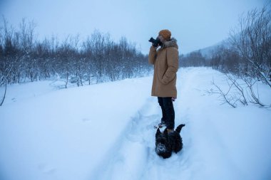 Bir adam kış yürüyüşünde köpeğinin resmini çeker.