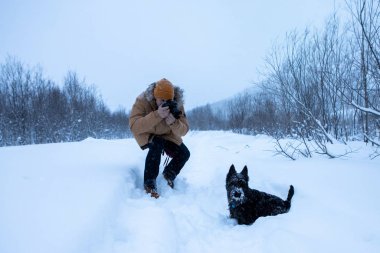 Bir adam kış yürüyüşünde köpeğinin resmini çeker.