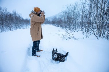 Bir adam kış yürüyüşünde köpeğinin resmini çeker.