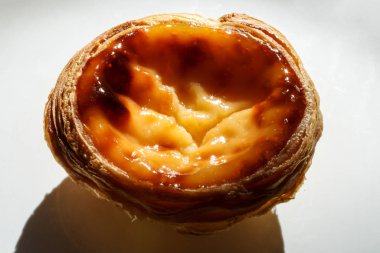 Beyaz tabakta kremalı, dokulu arka planda Portekiz pastası.