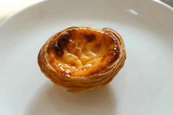 Quatro pasteis portugueses de bolo com creme sobre placa branca sobre fundo texturizado — Fotografia de Stock