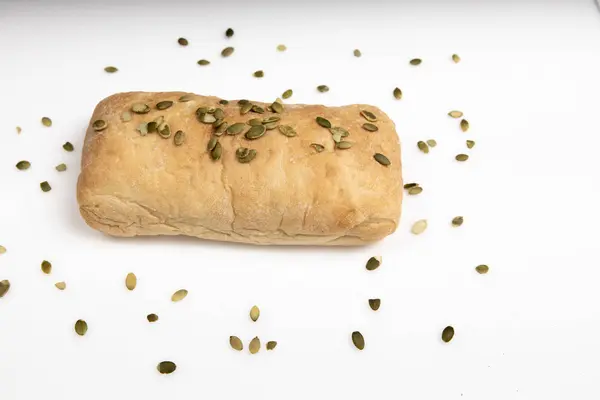 Pão ciabatta italiano está sozinho em um fundo branco com sementes de abóbora — Fotografia de Stock