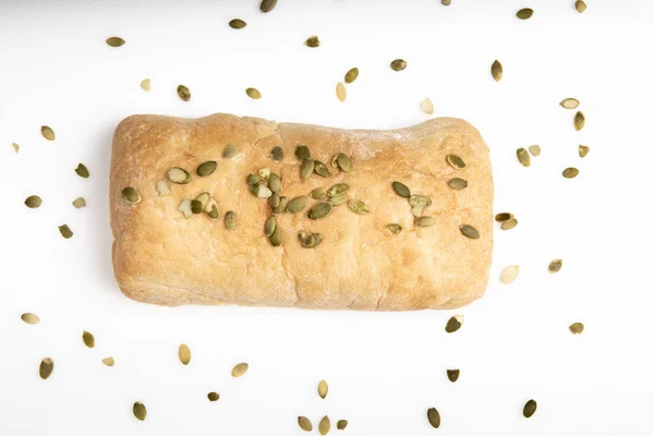 Pão ciabatta italiano está sozinho em um fundo branco com sementes de abóbora — Fotografia de Stock