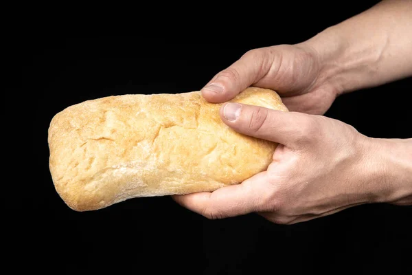 Fresh bread ciabatta in two male hands on black background — Stock Photo, Image