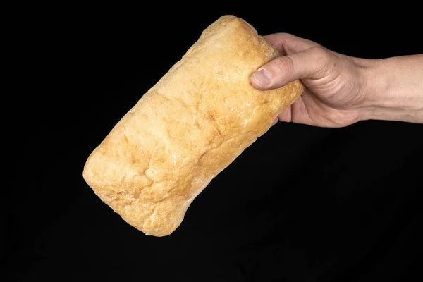 Fresh bread ciabatta in the male hand on black background. — Stock Photo, Image