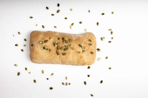 Pão ciabatta italiano está sozinho em um fundo branco com sementes de abóbora — Fotografia de Stock