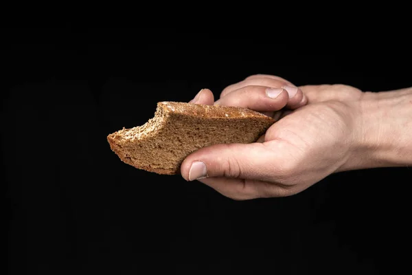 Man holds a bitten bread in his hand on black background