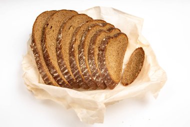 Çavdar ekmeği beyaz arka planda, ekmek kağıdının üzerinde parçalanmış olarak duruyor.