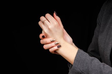 Woman applying hand cream on black background. Side view process of applying cosmetic cream. Feminine side composition with copy space for text
