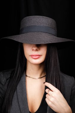 Beautiful woman portrait with a big hat. Vintage look. Fashion makeup. The hat covers half the face