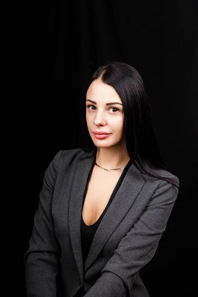Porträt einer jungen Geschäftsfrau in grauer Jacke auf schwarzem Hintergrund — Stockfoto