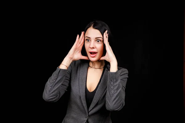 Young woman is angry. The girl wear casual grey jacket on a black background. Evil woman, hands on her sides — Stok fotoğraf