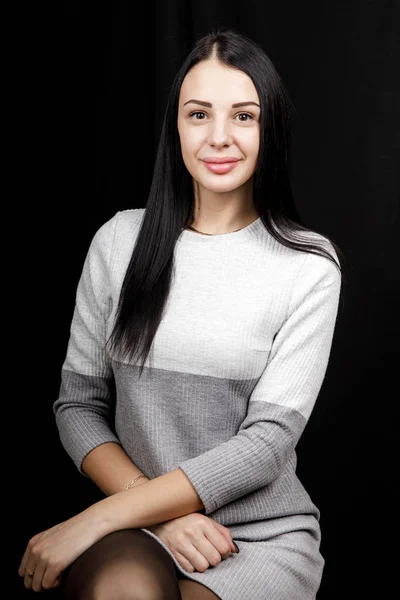 Retrato de mujer hermosa seria con el pelo negro, tiene un maquillaje mínimo, mira con calma a la cámara, usa jersey blanco, se levanta contra el fondo negro, siendo profundo en los pensamientos — Foto de Stock