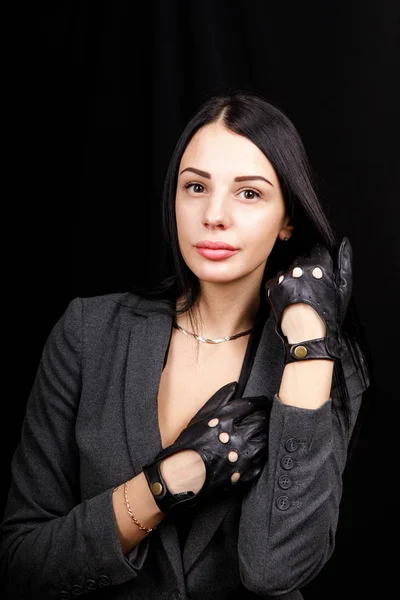 Портрет жінки руками в чорних шкіряних рукавичках без пальців на чорному тлі — стокове фото