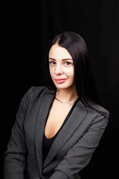 Porträt einer jungen Geschäftsfrau in grauer Jacke auf schwarzem Hintergrund — Stockfoto