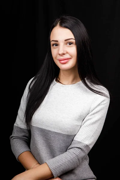 Retrato de mulher bonita grave com cabelo preto, tem maquiagem mínima, olha calmamente para a câmera, usa saltador branco, fica contra o fundo preto, sendo profundo nos pensamentos — Fotografia de Stock