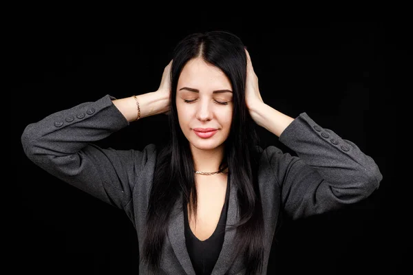 Confused woman holding hands on head over black studio background. Portrait of young serious girl closing her ears, hear no evil, deafness concept, copy space — ストック写真