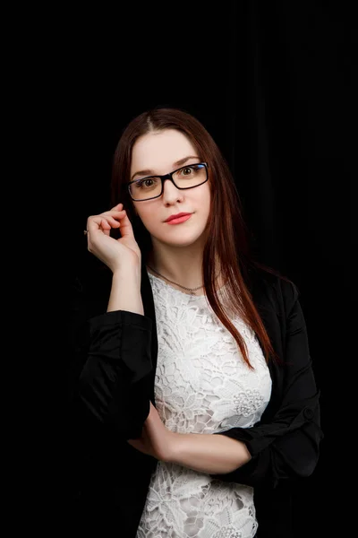 Retrato de una joven mujer de negocios con gafas en una chaqueta negra sobre fondo negro — Foto de Stock