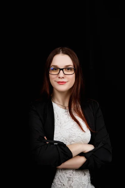 Retrato de una joven mujer de negocios con gafas en una chaqueta negra sobre fondo negro — Foto de Stock