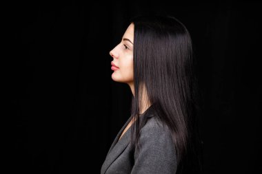 Profile portrait of a cute gorgeous girl with a beaming smile plump lips in casual dress on black background with copy space empty space