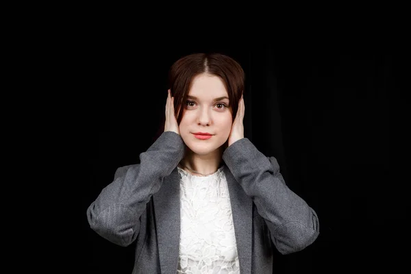 Confused woman holding hands on head over black studio background. Portrait of young serious girl closing her ears, hear no evil, deafness concept, copy space — Stok fotoğraf