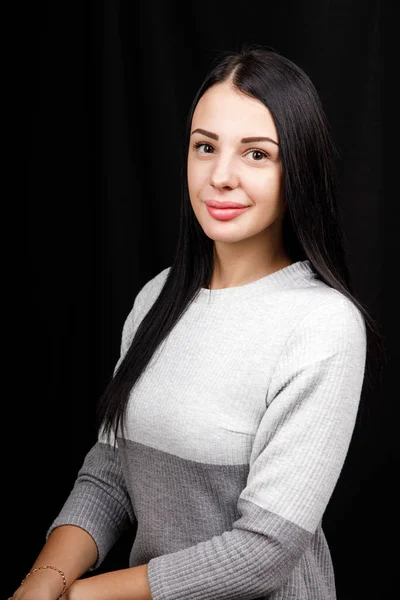 Porträt einer ernsthaften schönen Frau mit schwarzem Haar, minimalistisch geschminkt, blickt ruhig in die Kamera, trägt weißen Pullover, steht vor schwarzem Hintergrund, ist tief in Gedanken — Stockfoto