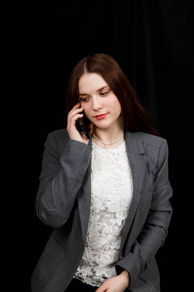 Joven blogger alegre y exitoso está hablando emocionalmente por teléfono. Hermosa mujer joven en chaqueta gris casual está sosteniendo el teléfono inteligente — Foto de Stock