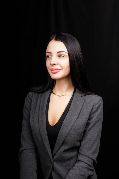 Retrato de una joven mujer de negocios con chaqueta gris sobre fondo negro — Foto de Stock