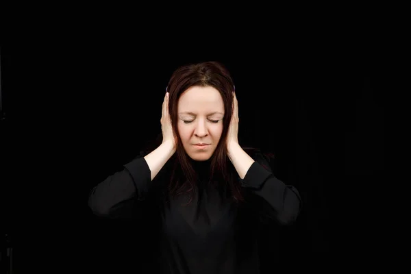 Confused woman holding hands on head over black studio background. Portrait of young serious girl closing her ears, hear no evil, deafness concept, copy space — ストック写真