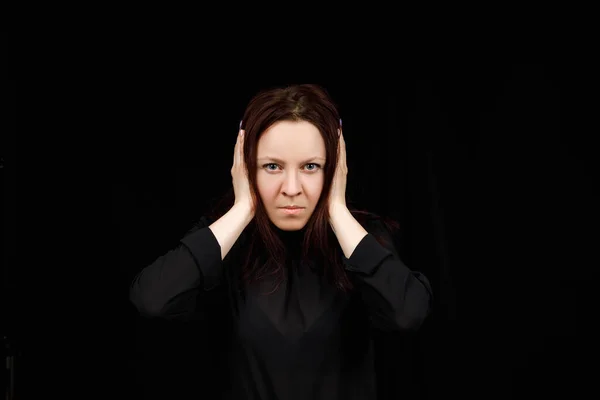 Confused woman holding hands on head over black studio background. Portrait of young serious girl closing her ears, hear no evil, deafness concept, copy space — Stok fotoğraf