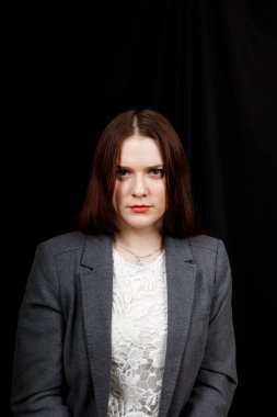 Young woman is angry. The girl wear casual sweeter on a black background. Evil woman, hands on her sides