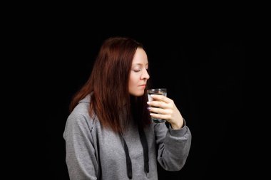 Su içen bir kadının portresi. Gülümseyen kız. Siyah arkaplanda bir portre