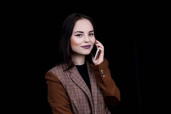 Joven blogger de moda alegre y exitosa está hablando emocionalmente por teléfono. Hermosa mujer joven en chaqueta gris casual está sosteniendo el teléfono inteligente — Foto de Stock
