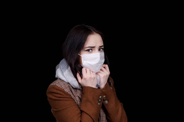 Girl in a scarf and a medical mask is afraid of contracting the virus