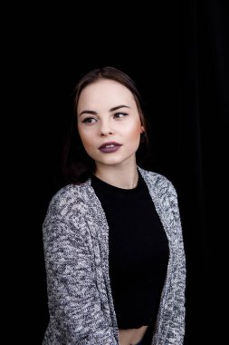 Sıradan giyinmiş tatlı kız siyah arka planda gülümsüyor.