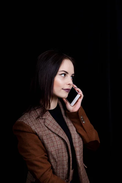 Neşeli ve başarılı genç kadın moda blogcusu telefonda duygusal olarak konuşuyor. Gri ceketli güzel bir kadın elinde akıllı telefon tutuyor. — Stok fotoğraf