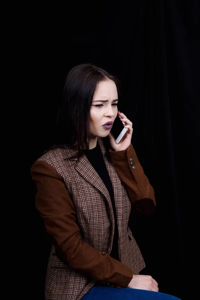 Neşeli ve başarılı genç kadın moda blogcusu telefonda duygusal olarak konuşuyor. Gri ceketli güzel bir kadın elinde akıllı telefon tutuyor. — Stok fotoğraf